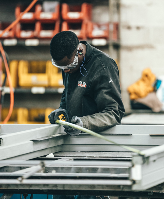 man in personal safety gear measuring object for squareness