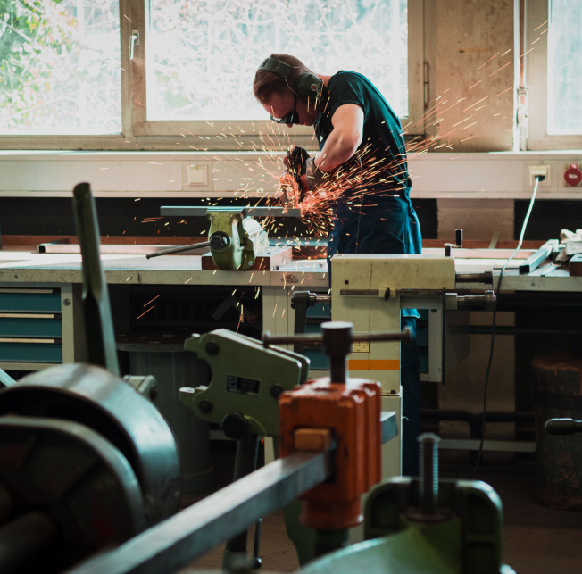 man grinding work piece in vise