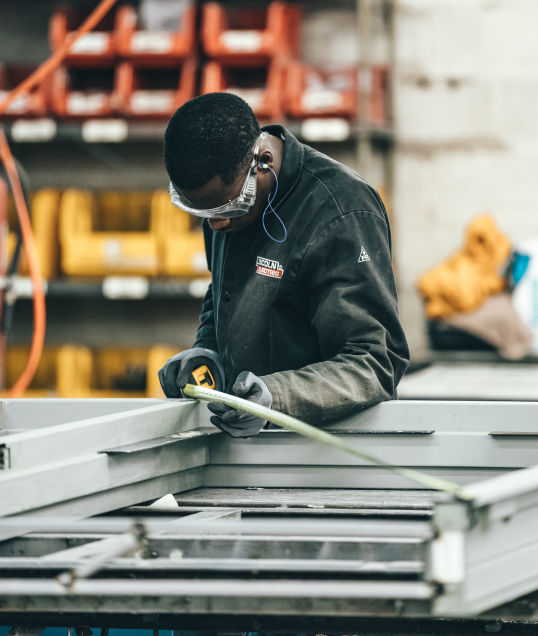 man in personal safety gear measuring object for squareness