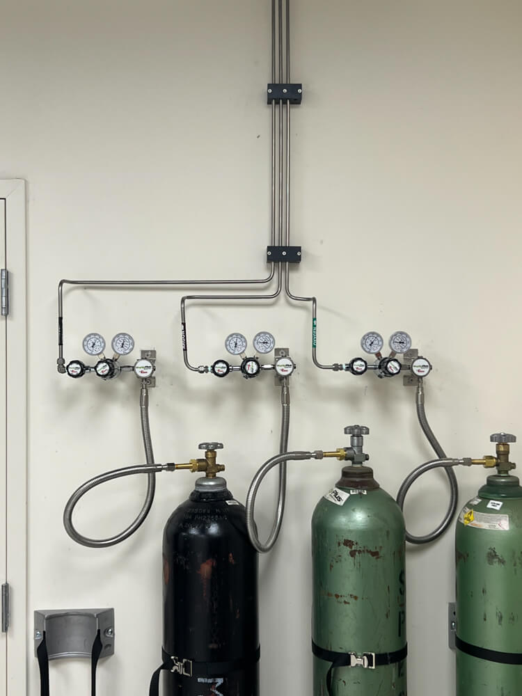 gas cylinders attached to wall mounted piping for refilling