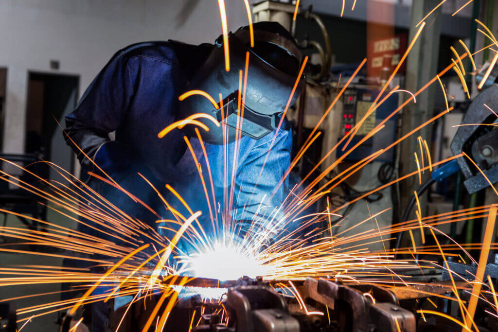 man in helmet and jacket welding